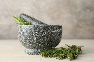 Photo of Stone mortar with rosemary and pestle on light table, closeup