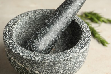Photo of Stone mortar with rosemary and pestle on light table, closeup