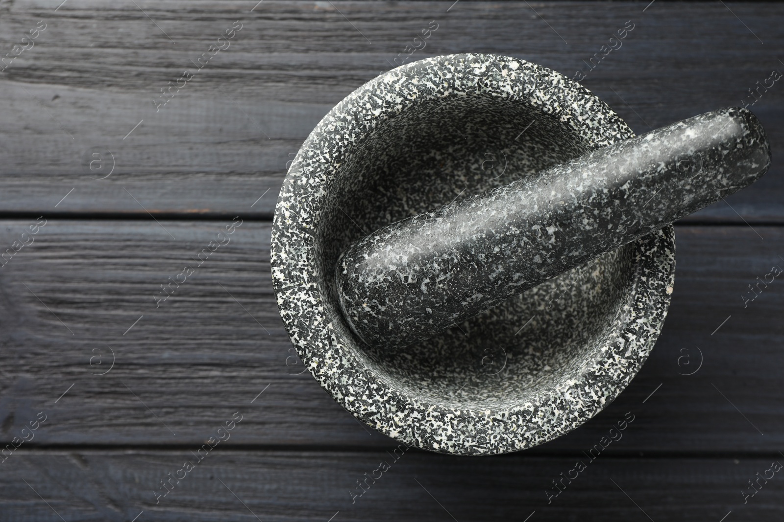 Stone mortar and pestle on black wooden table, top view Photo of Stone mortar and pestle on black wooden table, top view