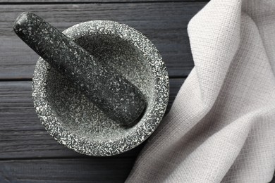 Photo of Stone mortar and pestle on black wooden table, top view