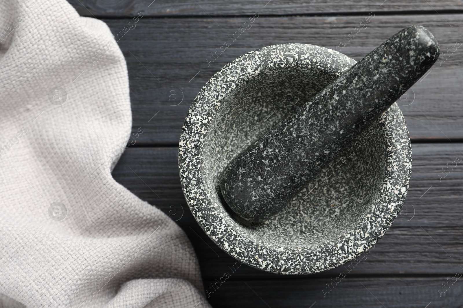 Stone mortar and pestle on black wooden table, top view Photo of Stone mortar and pestle on black wooden table, top view