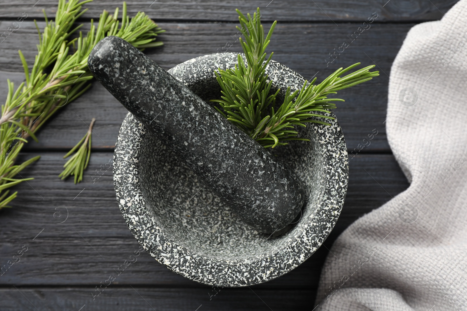 Stone mortar with rosemary and pestle on black wooden table, flat lay Photo of Stone mortar with rosemary and pestle on black wooden table, flat lay