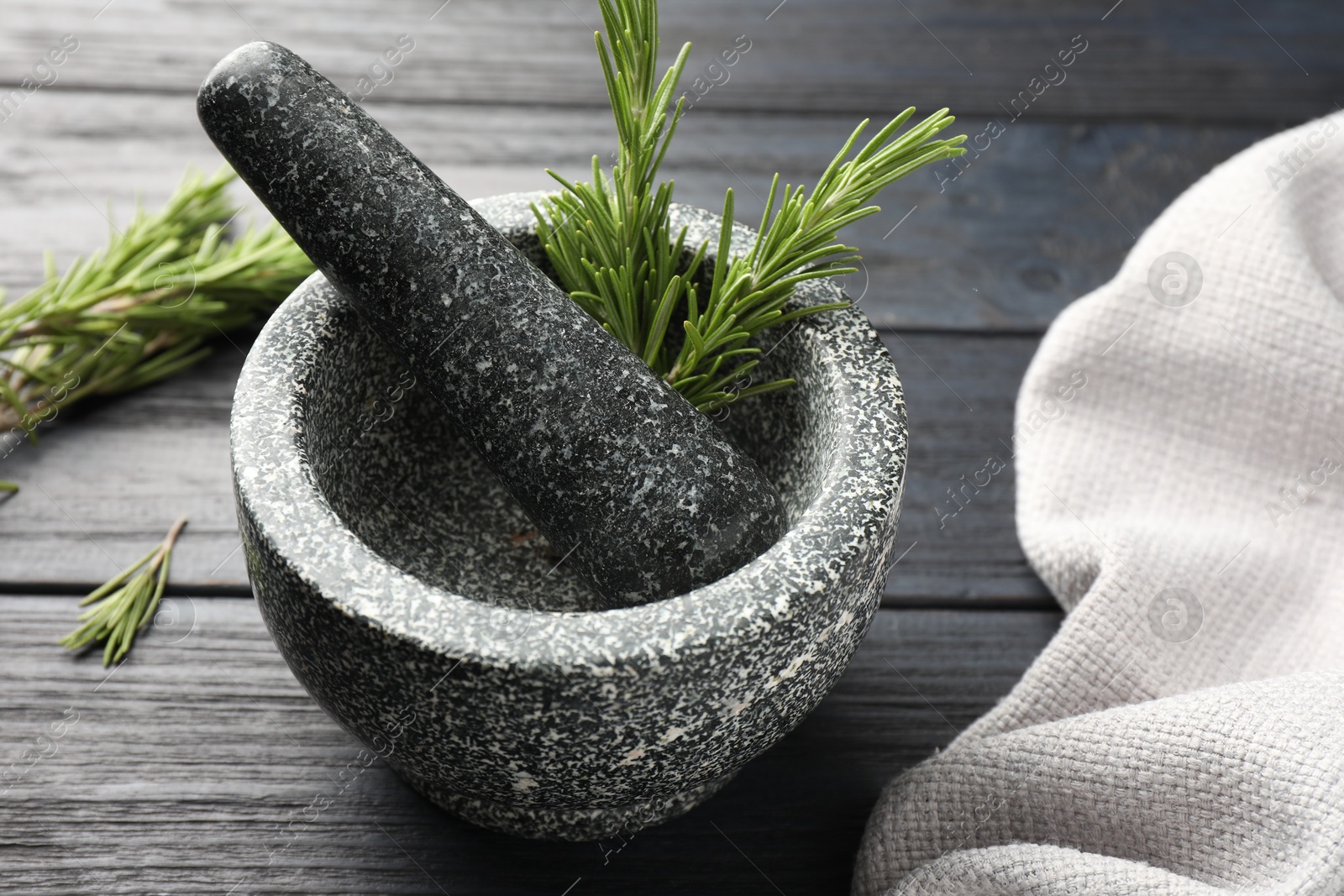 Stone mortar with rosemary and pestle on black wooden table, closeup Photo of Stone mortar with rosemary and pestle on black wooden table, closeup