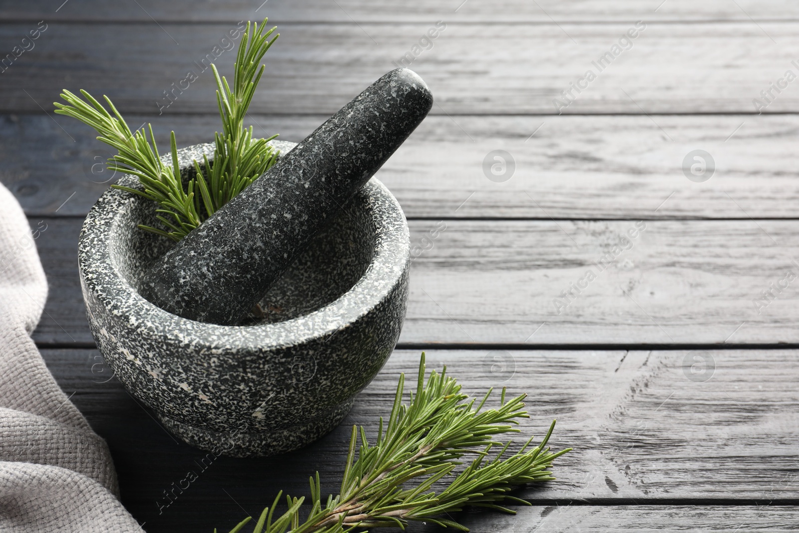 Stone mortar with rosemary and pestle on black wooden table, closeup. Space for text Photo of Stone mortar with rosemary and pestle on black wooden table, closeup. Space for text