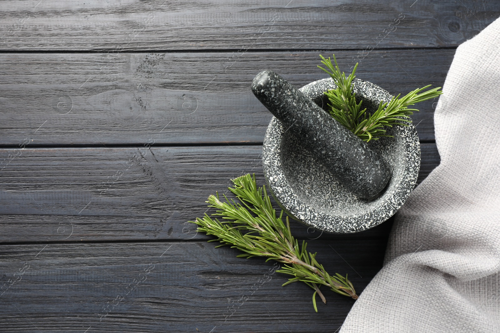 Stone mortar with rosemary and pestle on black wooden table, flat lay. Space for text Photo of Stone mortar with rosemary and pestle on black wooden table, flat lay. Space for text