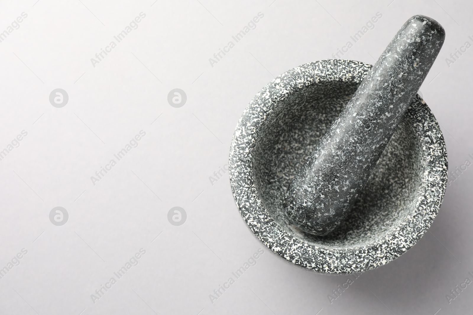 Stone mortar and pestle on light grey background, top view. Space for text Photo of Stone mortar and pestle on light grey background, top view. Space for text