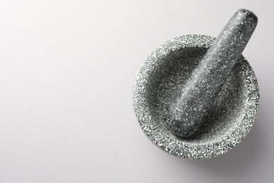 Photo of Stone mortar and pestle on light grey background, top view. Space for text