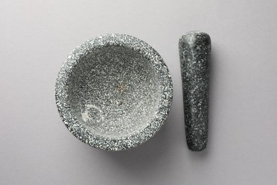 Photo of Stone mortar and pestle on light grey background, top view