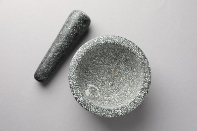 Photo of Stone mortar and pestle on light grey background, top view