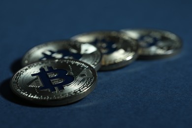 Photo of Cryptocurrency. Silver bitcoins on dark blue background, closeup