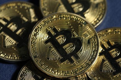 Photo of Cryptocurrency. Golden bitcoins on dark blue background, closeup