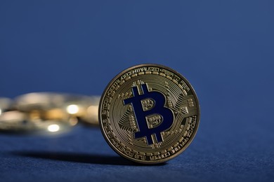 Photo of Cryptocurrency. Golden bitcoins on dark blue background, closeup
