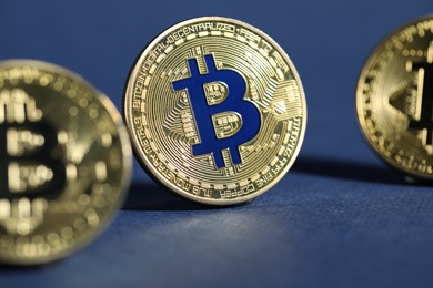 Photo of Cryptocurrency. Golden bitcoins on dark blue background, closeup