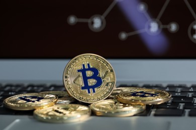 Photo of Cryptocurrency. Golden bitcoins on laptop, closeup view