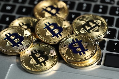 Photo of Cryptocurrency. Golden bitcoins on laptop, closeup view