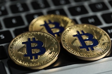 Photo of Cryptocurrency. Golden bitcoins on laptop, closeup view