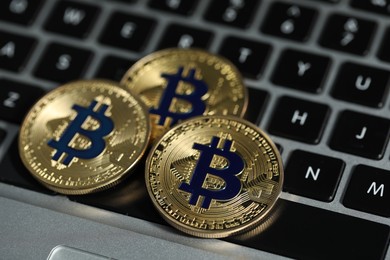 Photo of Cryptocurrency. Golden bitcoins on laptop, closeup view