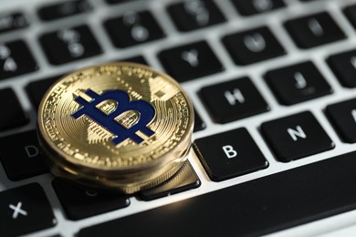 Photo of Cryptocurrency. Golden bitcoins on laptop, closeup. Space for text