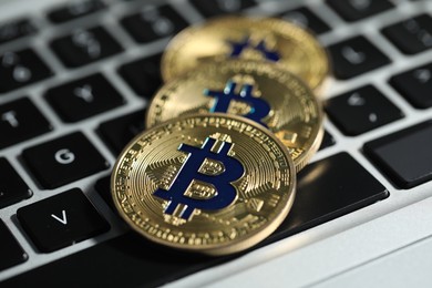 Photo of Cryptocurrency. Golden bitcoins on laptop, closeup view
