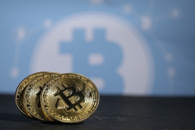 Photo of Cryptocurrency. Three bitcoins on black table, closeup. Space for text