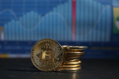 Photo of Cryptocurrency. Bitcoins on black table against data charts, closeup