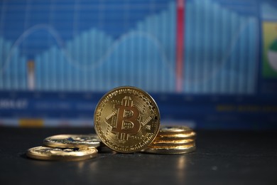 Photo of Cryptocurrency. Bitcoins on black table against data charts, closeup