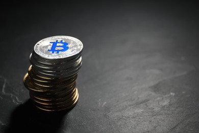 Photo of Cryptocurrency. Stack of bitcoins on black table, closeup. Space for text