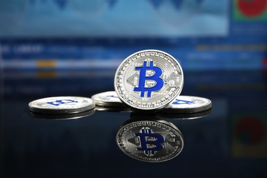 Photo of Cryptocurrency. Silver bitcoins on mirror surface, closeup