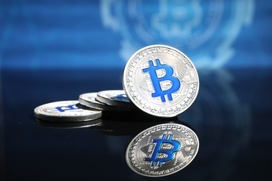 Photo of Cryptocurrency. Silver bitcoins on mirror surface, closeup