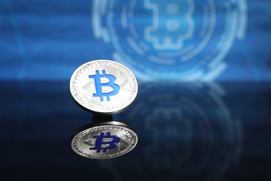 Photo of Cryptocurrency. One bitcoin on mirror surface, closeup. Space for text
