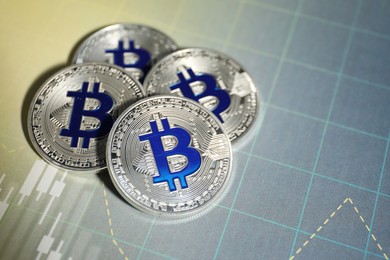 Photo of Cryptocurrency. Bitcoins on data charts, above view. Space for text