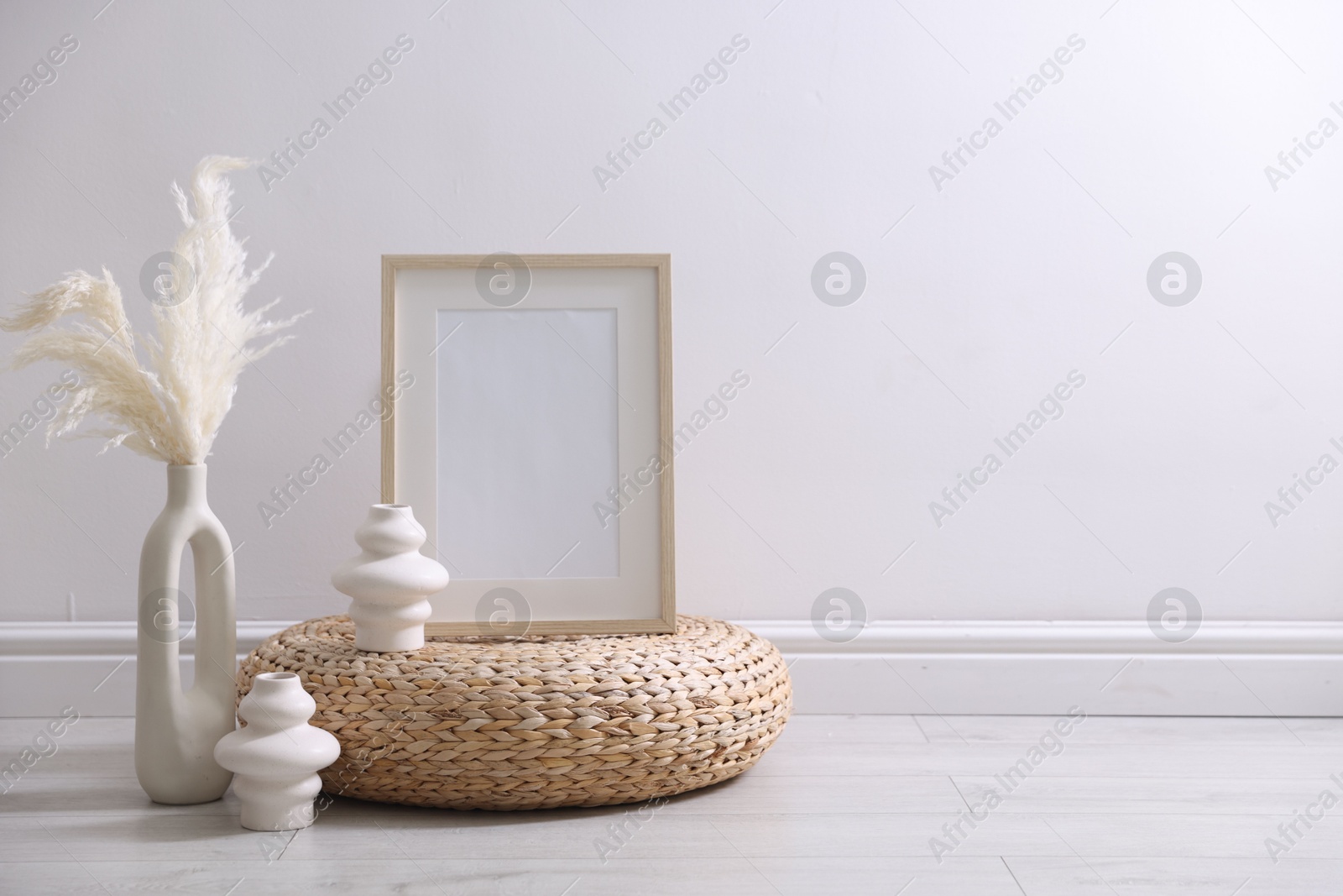 Empty picture frame and stylish home decor near white wall indoors Photo of Empty picture frame and stylish home decor near white wall indoors