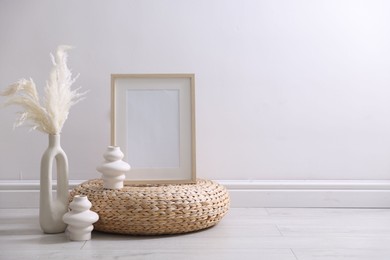 Photo of Empty picture frame and stylish home decor near white wall indoors
