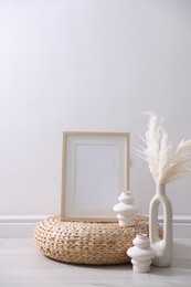 Photo of Empty picture frame and stylish home decor near white wall indoors