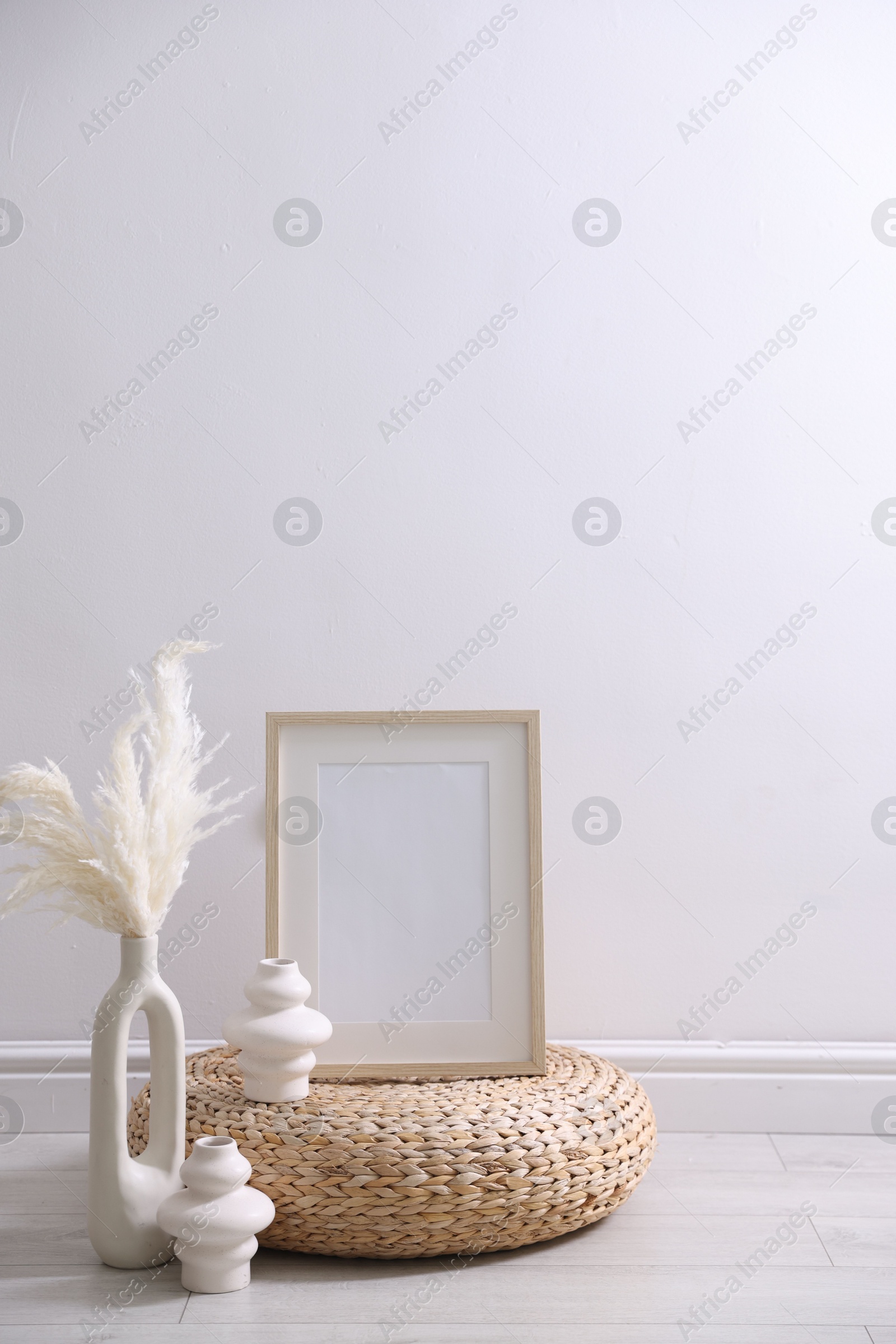 Empty picture frame and stylish home decor near white wall indoors Photo of Empty picture frame and stylish home decor near white wall indoors
