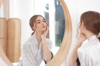 Photo of Beautiful woman looking at herself in mirror indoors