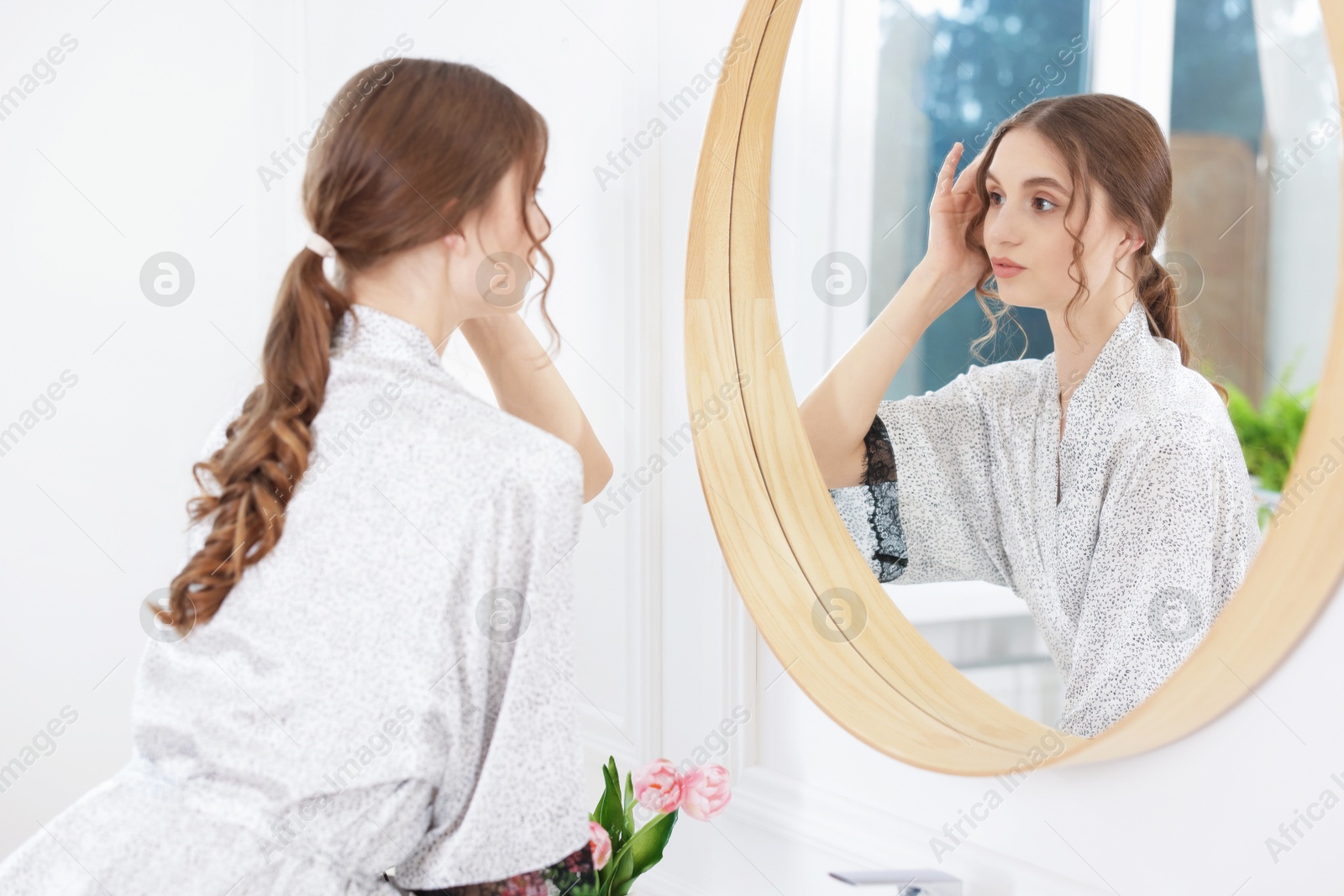 Beautiful woman looking at herself in mirror indoors Photo of Beautiful woman looking at herself in mirror indoors