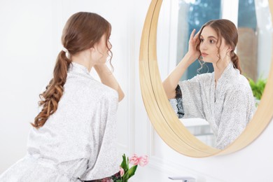 Photo of Beautiful woman looking at herself in mirror indoors