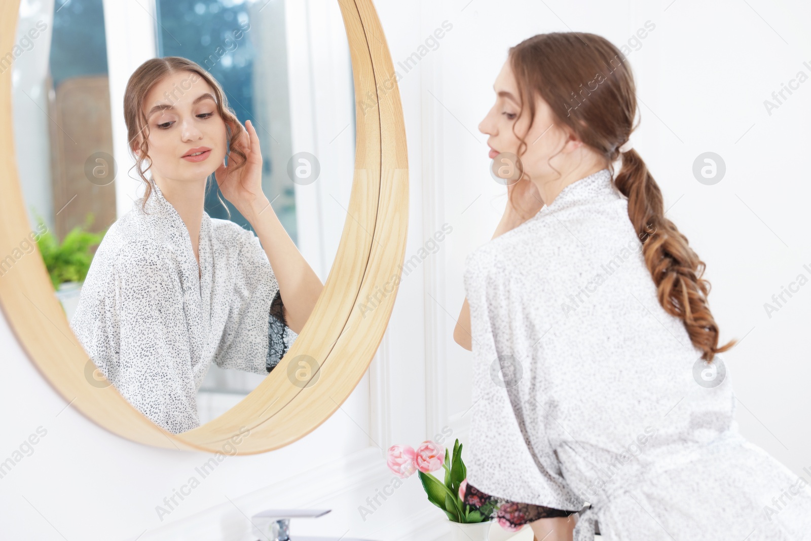 Beautiful woman looking at herself in mirror indoors Photo of Beautiful woman looking at herself in mirror indoors