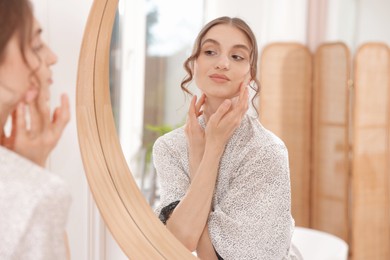 Photo of Beautiful woman looking at herself in mirror indoors