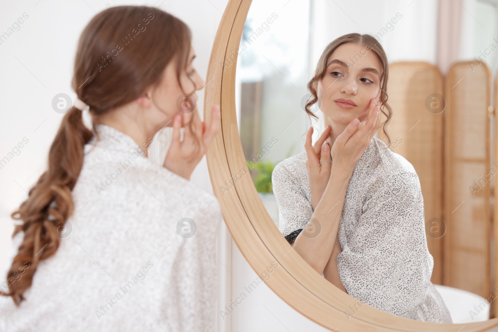 Beautiful woman looking at herself in mirror indoors Photo of Beautiful woman looking at herself in mirror indoors