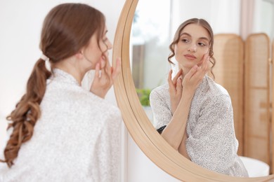 Photo of Beautiful woman looking at herself in mirror indoors