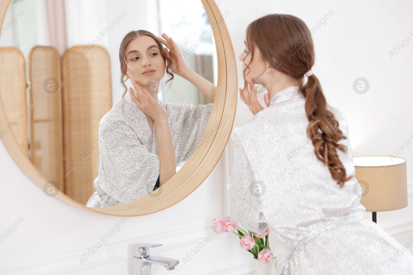 Beautiful woman looking at herself in mirror indoors Photo of Beautiful woman looking at herself in mirror indoors