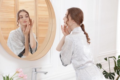 Photo of Beautiful woman looking at herself in mirror indoors