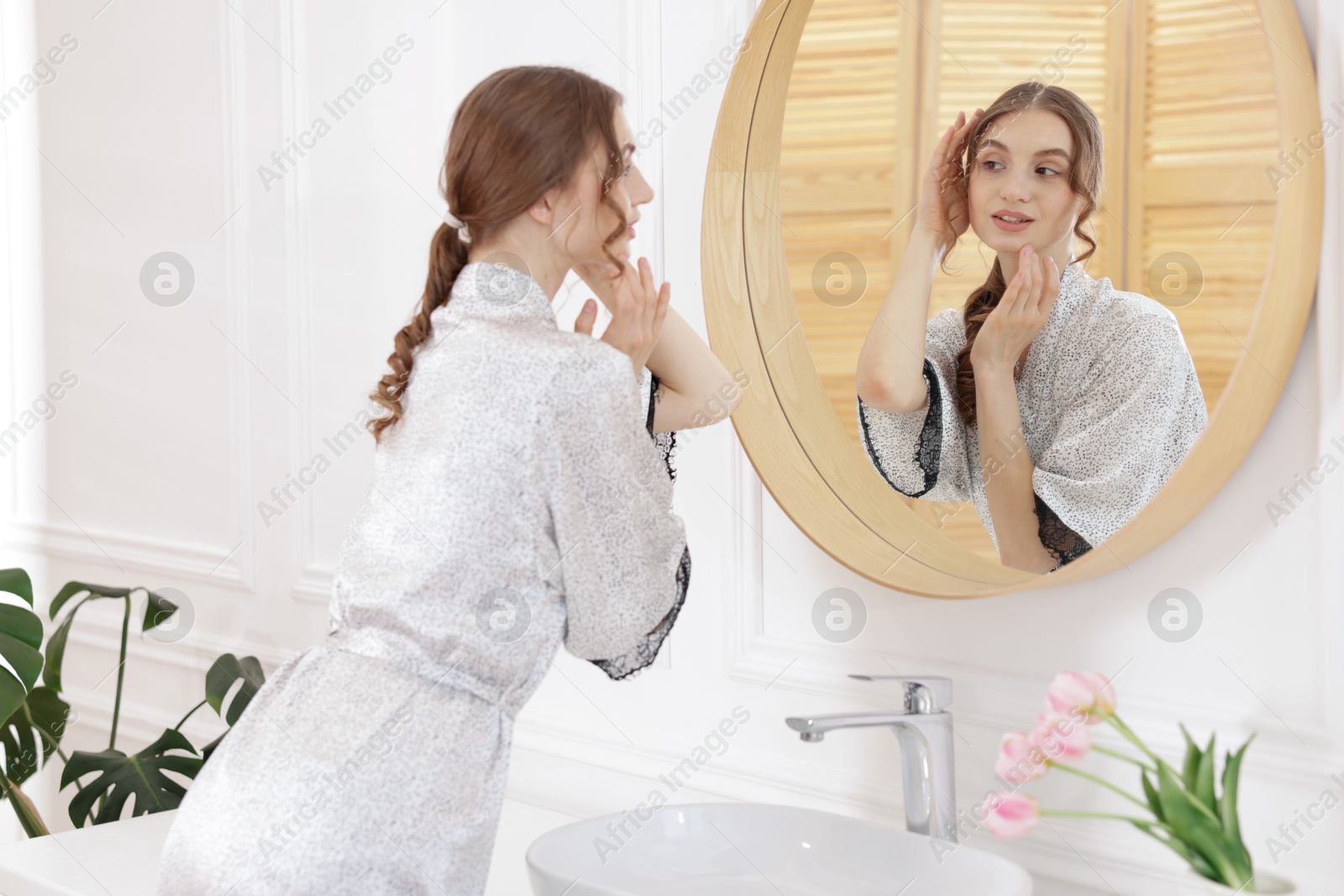 Beautiful woman looking at herself in mirror indoors Photo of Beautiful woman looking at herself in mirror indoors