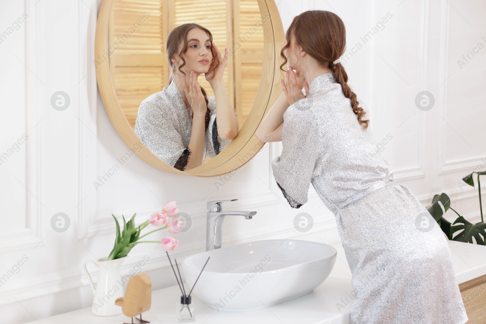 Beautiful woman looking at herself in mirror indoors Photo of Beautiful woman looking at herself in mirror indoors