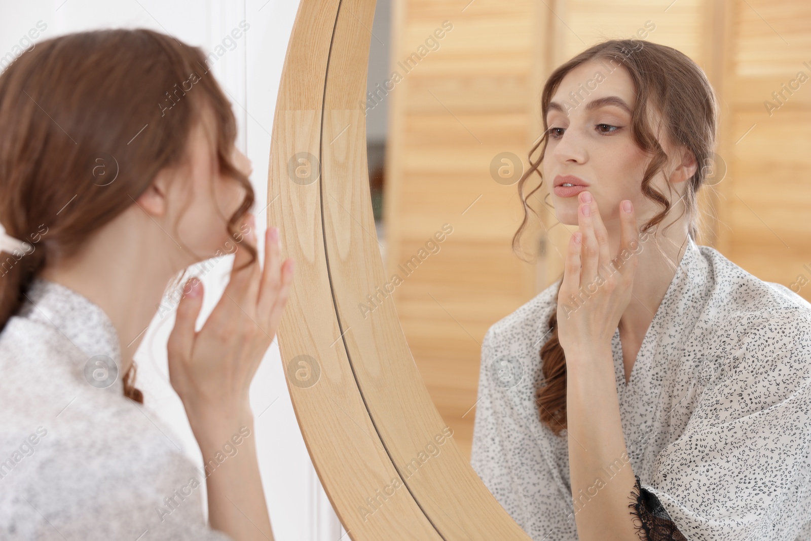 Beautiful woman looking at herself in mirror indoors Photo of Beautiful woman looking at herself in mirror indoors