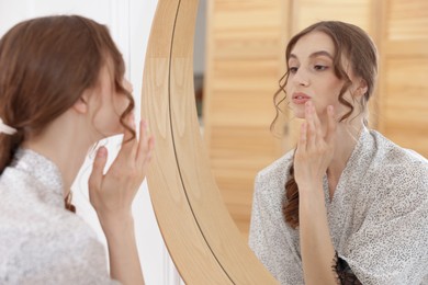 Photo of Beautiful woman looking at herself in mirror indoors