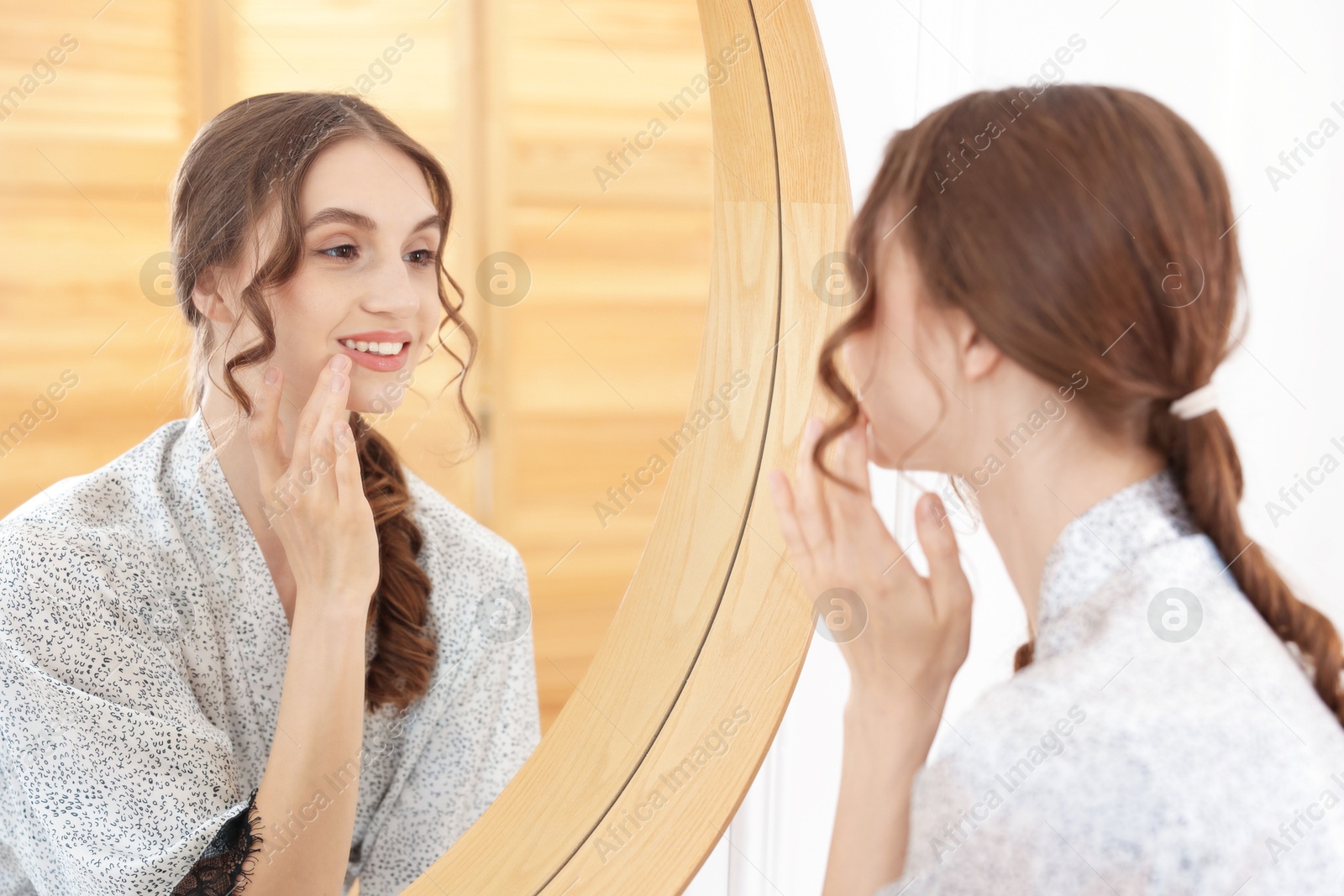 Beautiful woman looking at herself in mirror indoors Photo of Beautiful woman looking at herself in mirror indoors
