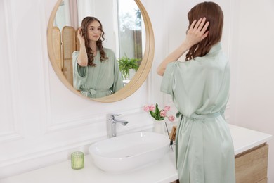 Photo of Beautiful woman looking at herself in mirror indoors